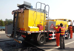 Operadores realizando reparaciones viales con máquina de bacheo eficiente